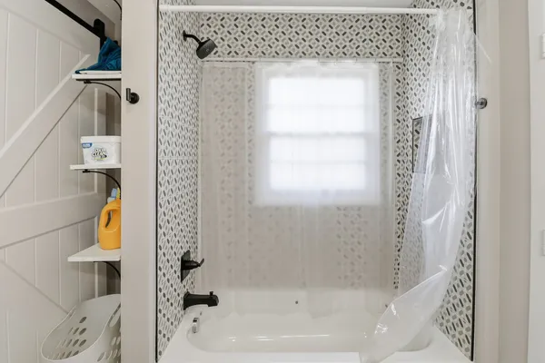 a bath tub sitting next to a white toilet and a window