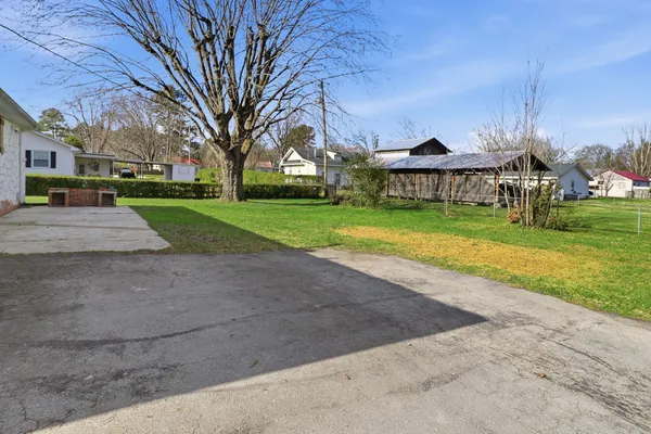 a view of a house with a big yard and large trees