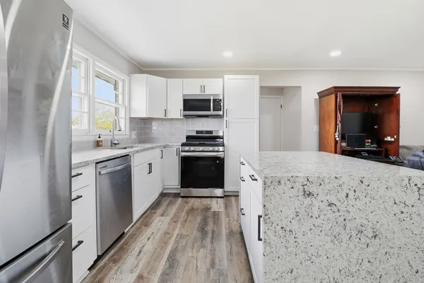 a kitchen with granite countertop a stove top oven a sink dishwasher and a refrigerator with wooden floor