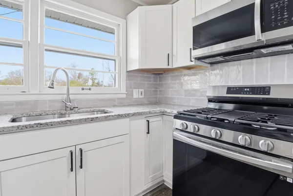 a kitchen with granite countertop a sink cabinets and stainless steel appliances