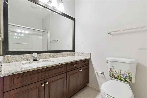 a bathroom with a granite countertop sink a toilet and a mirror