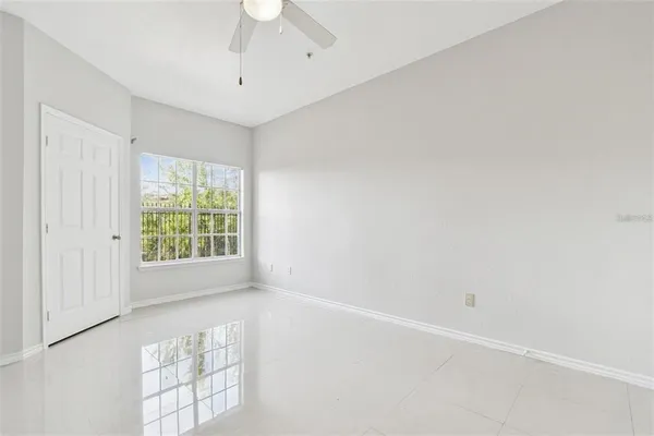 an empty room with windows and chandelier fan