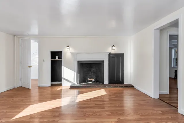 a view of empty room with wooden floor and fireplace