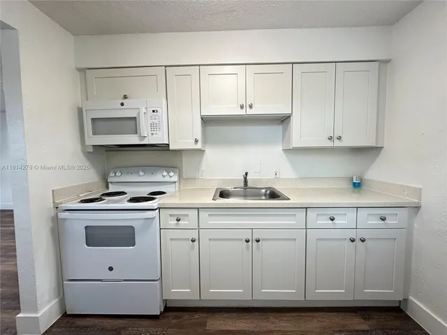 a kitchen with white cabinets and white appliances