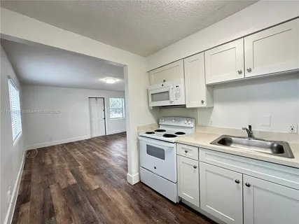 a kitchen with white cabinets stove and sink