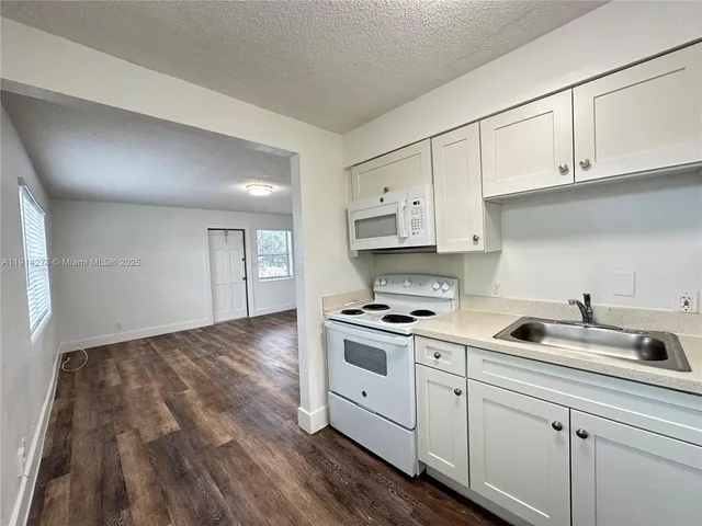 a kitchen with white cabinets stove and sink