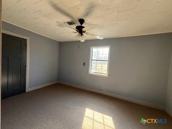 an empty room with windows and chandelier fan