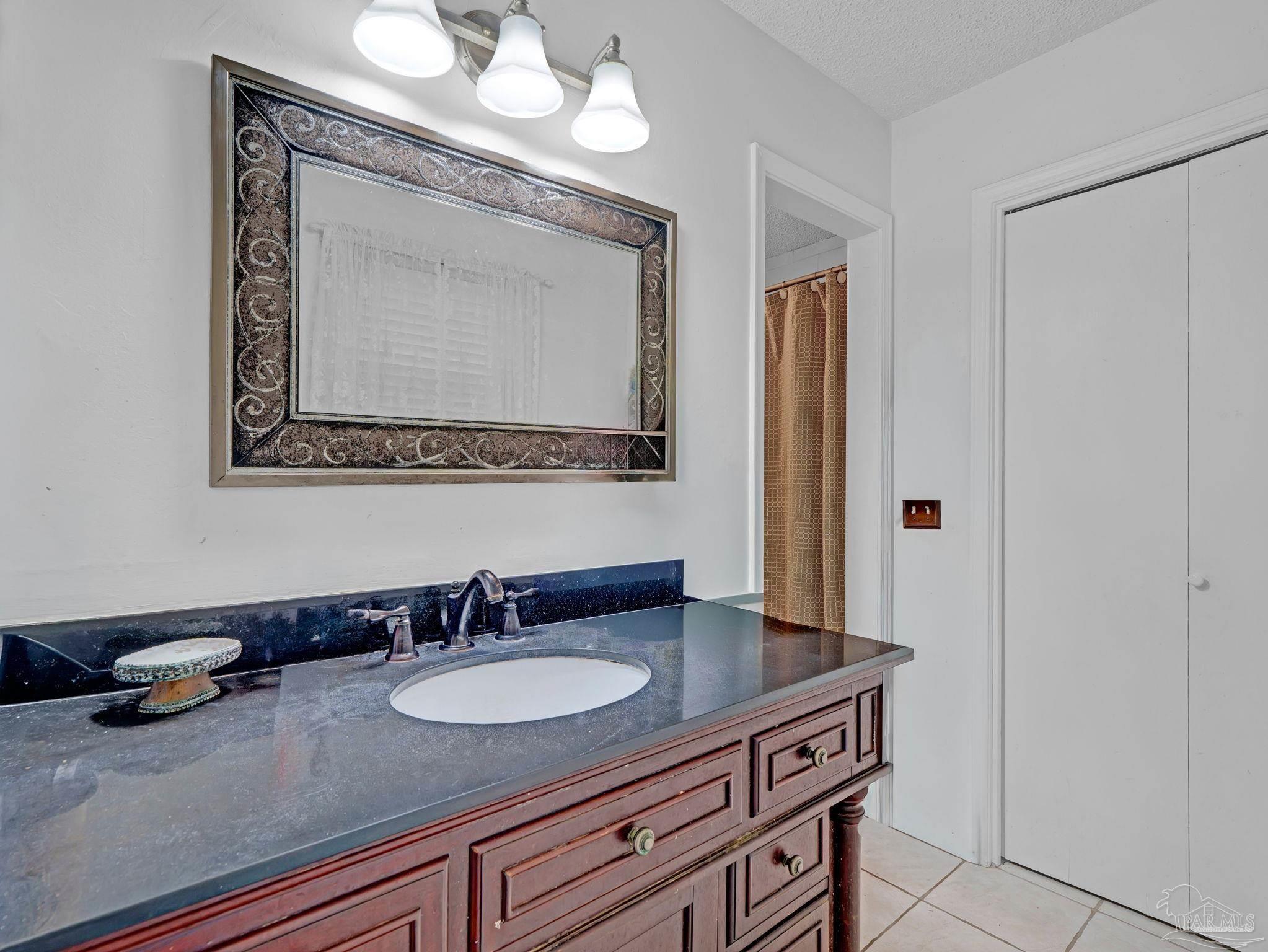 4112 Croydon Road Pensacola, FL 32514 - Photo 11 of 25 a bathroom with a granite countertop sink a mirror and a vanity