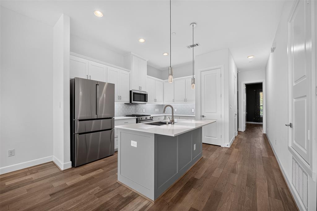 5015 Meridian Lane, Unit 2102 Addison, TX 75001 - Photo 6 of 36 Modern kitchen featuring an island with a light-toned countertop, stainless steel appliances, white cabinetry, recessed lighting, and wood-finish flooring