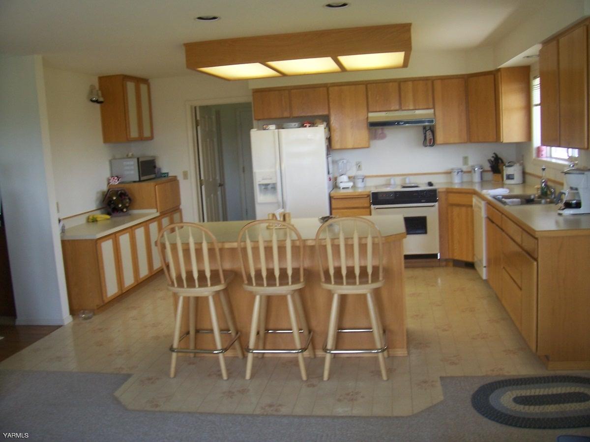 140 Faucher Road Yakima, WA 98901 - Photo 4 of 13 a kitchen with stainless steel appliances kitchen island granite countertop a table chairs sink and cabinets