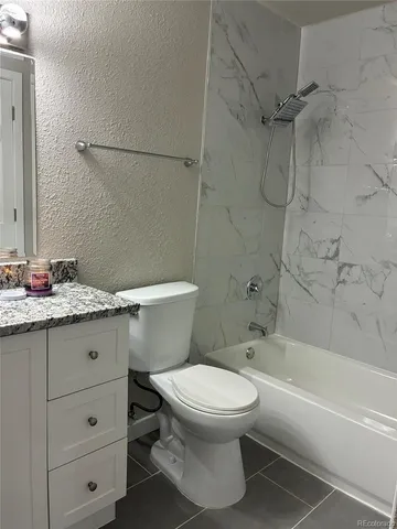 a bathroom with a granite countertop toilet a sink and bathtub