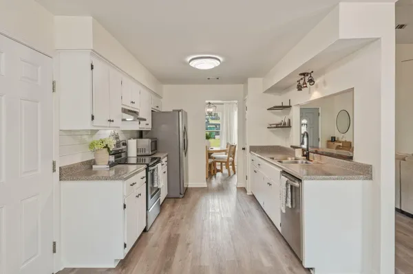 a large kitchen with stainless steel appliances granite countertop a lot of counter space and wooden floors