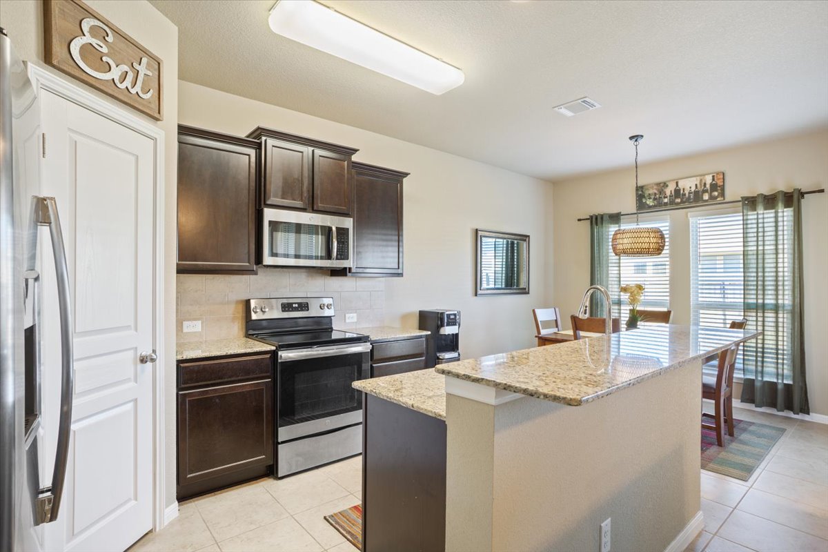 1149 Spring Terrace Loop Temple, TX 76502 - Photo 13 of 25 Modern kitchen with granite countertops, stainless steel appliances, rich espresso cabinetry, and breakfast bar seating.