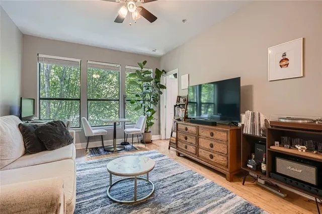 a living room with furniture a flat screen tv and a floor to ceiling window