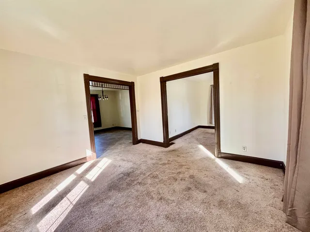 a view of an empty room with window and chandelier fan