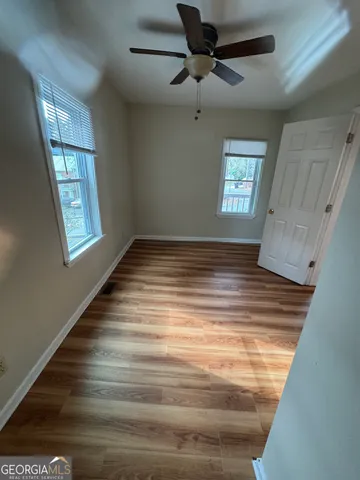 a view of empty room with wooden floor and fan