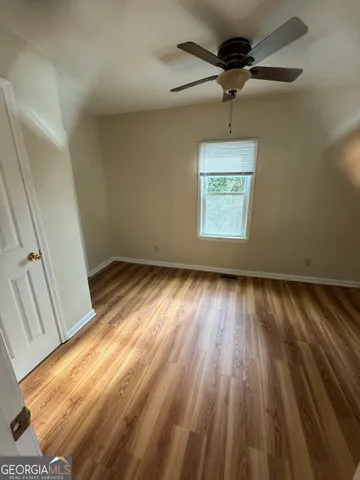 a view of room with window ceiling fan and hardwood floor