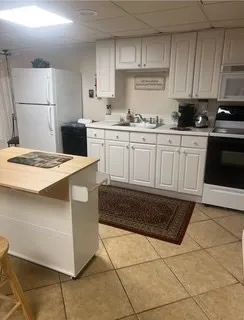 a kitchen with a sink a stove top oven and white cabinets
