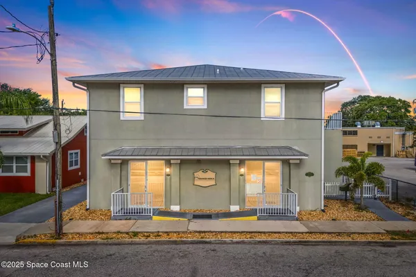 a view of a house with a yard and large tree