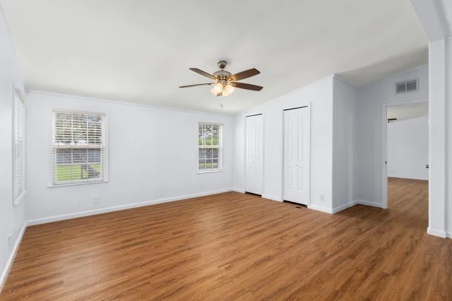 a view of empty room with wooden floor and fan