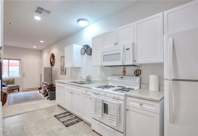 a kitchen with kitchen island granite countertop a sink a stove a refrigerator and white cabinets