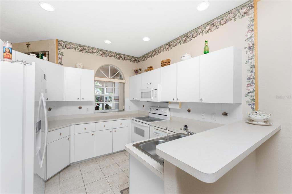 10214 Windsong Road Punta Gorda, FL 33955 - Photo 14 of 68 a kitchen with white cabinets and white appliances