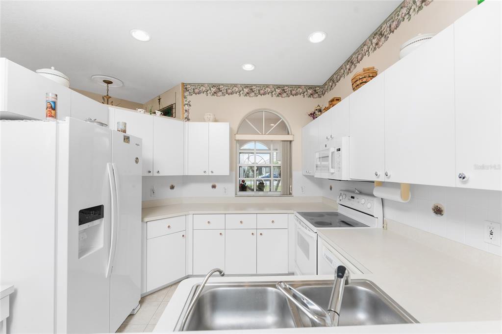 10214 Windsong Road Punta Gorda, FL 33955 - Photo 15 of 68 a kitchen with white cabinets and refrigerator