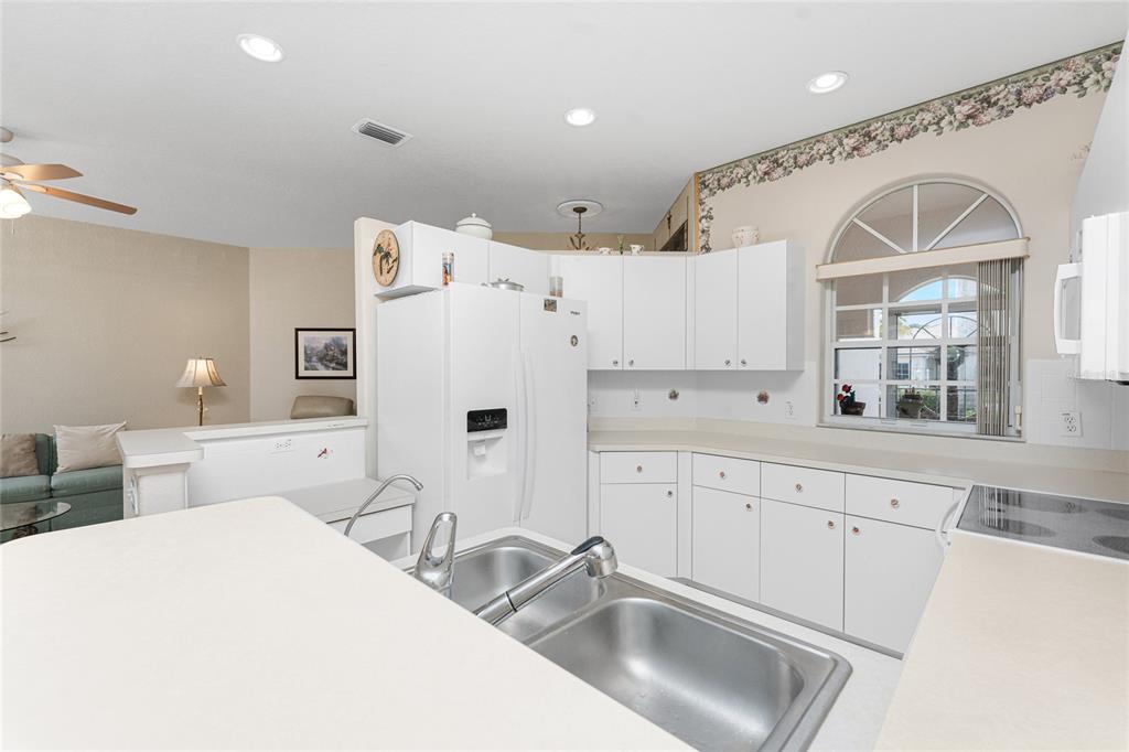 10214 Windsong Road Punta Gorda, FL 33955 - Photo 16 of 68 a kitchen with white cabinets and white appliances