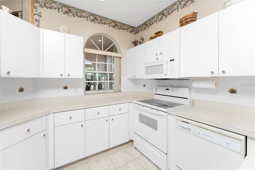 10214 Windsong Road Punta Gorda, FL 33955 - Photo 17 of 68 a kitchen with white cabinets and white appliances