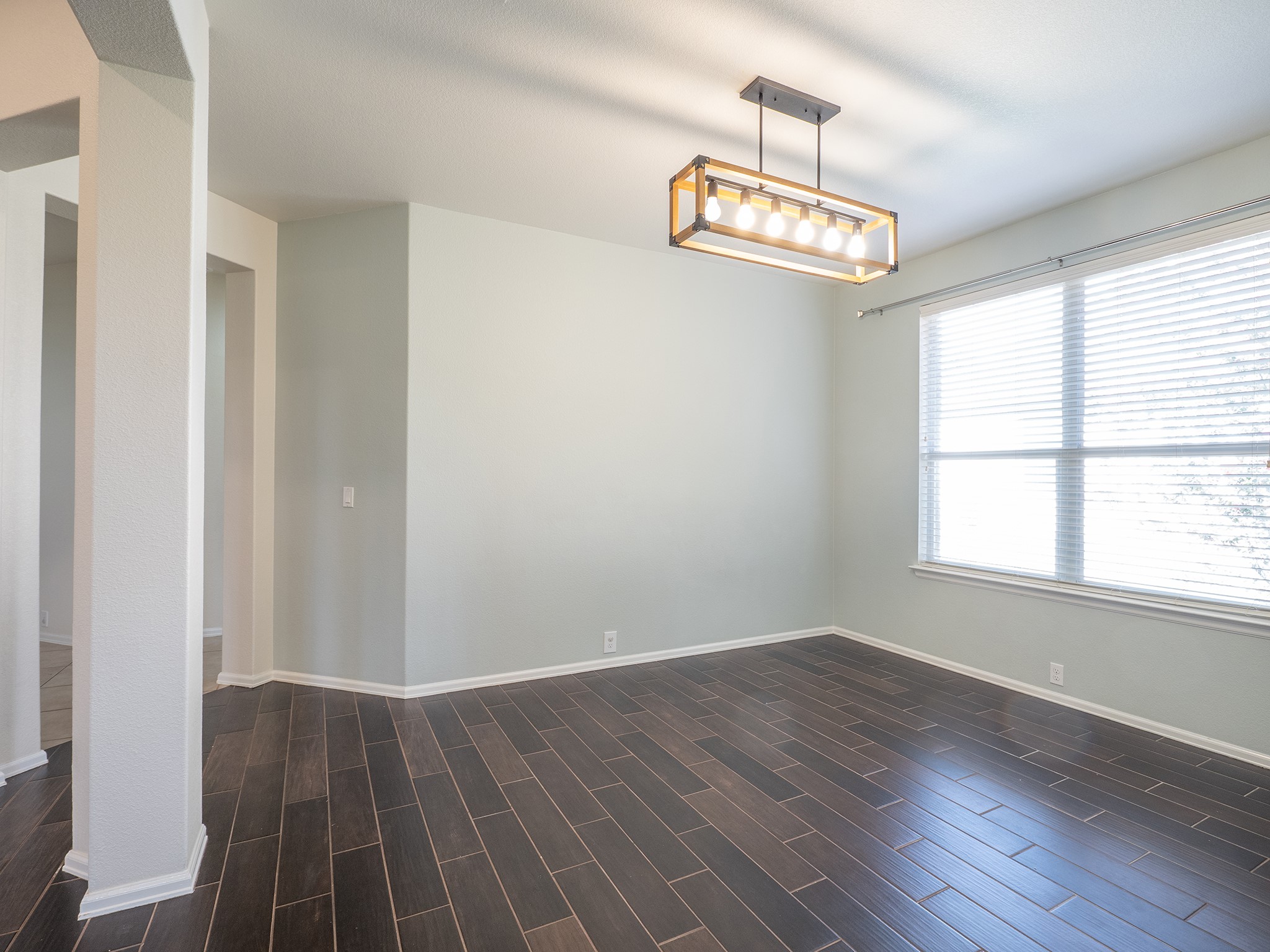 572 Big Meadow Road Austin, TX 78737 - Photo 10 of 32 A refined dining space features wood-look tile flooring and an elegant linear chandelier, perfect for entertaining.