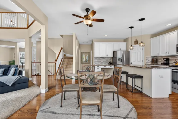 a kitchen with stainless steel appliances granite countertop a stove a sink a microwave a refrigerator with white cabinets and wooden floor