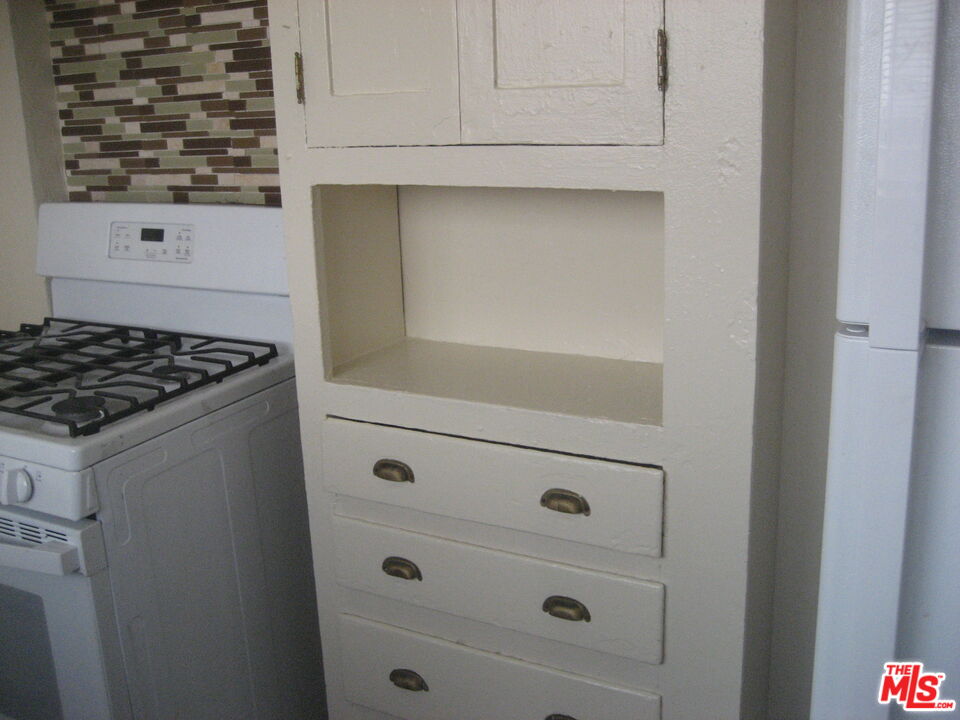105 West 106th Street, Unit 109 Los Angeles, CA 90003 - Photo 14 of 19 a kitchen with white cabinets and a stove with wooden floor