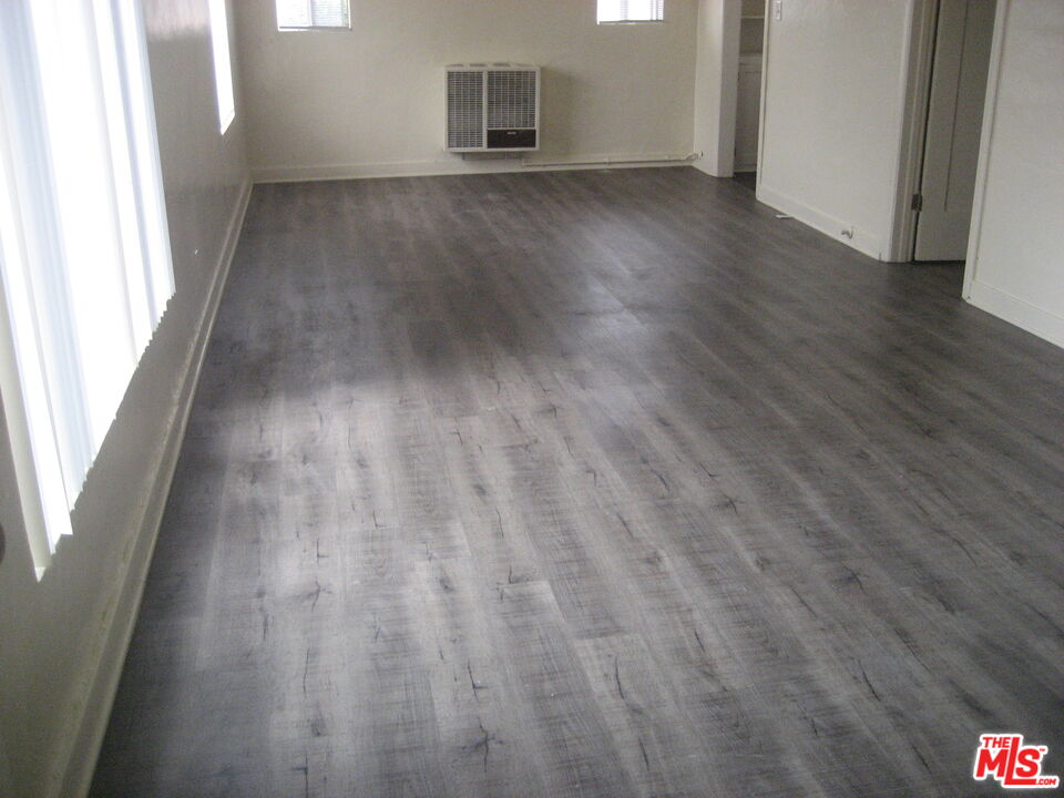 105 West 106th Street, Unit 109 Los Angeles, CA 90003 - Photo 4 of 19 an empty room with wooden floor and windows