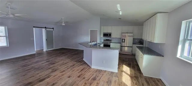 a kitchen with kitchen island wooden floors appliances and cabinets