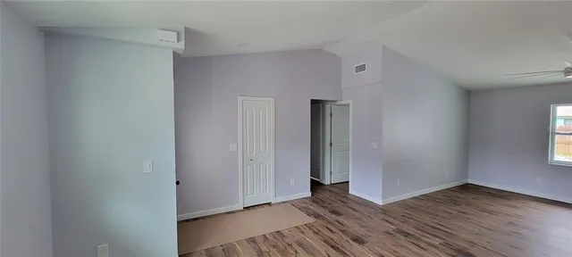 a view of an empty room with wooden floor and a window