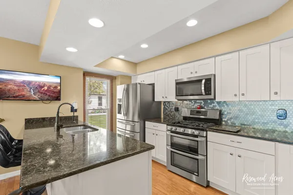 a kitchen with stainless steel appliances granite countertop a sink a stove counter space and cabinets
