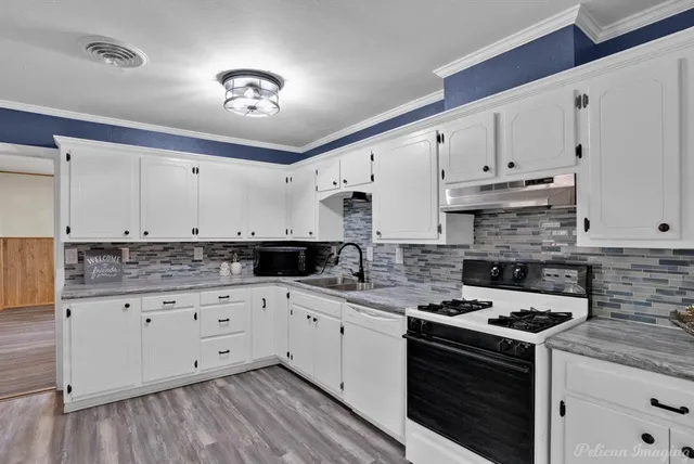 a kitchen with granite countertop a stove sink and cabinets