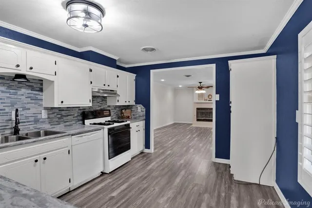 a kitchen with stainless steel appliances granite countertop a sink cabinets and wooden floor