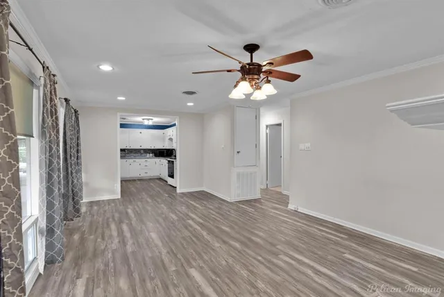 a view of an empty room with a window and wooden floor