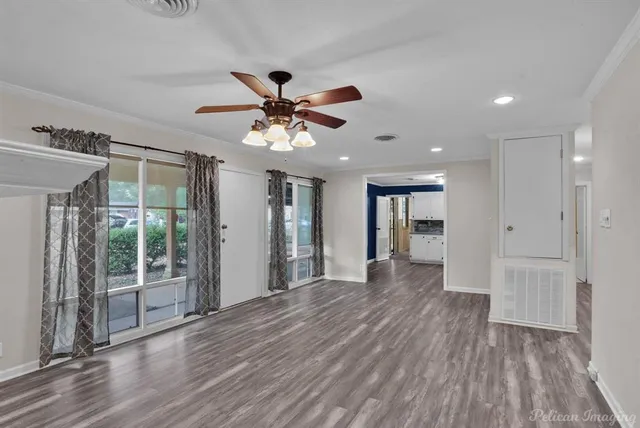 a view of an empty room with wooden floor and a window