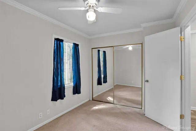 an empty room with closet and a chandelier fan