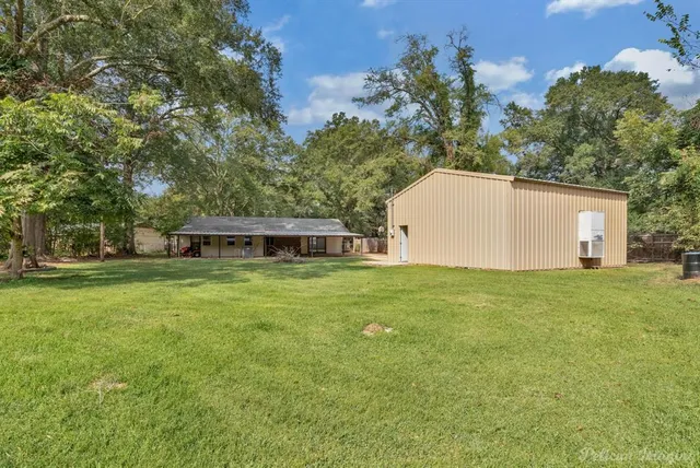 a view of a yard in front of a house with large trees