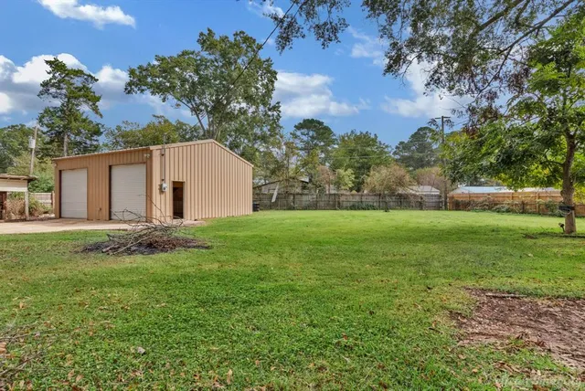 a backyard of a house with plants and large tree