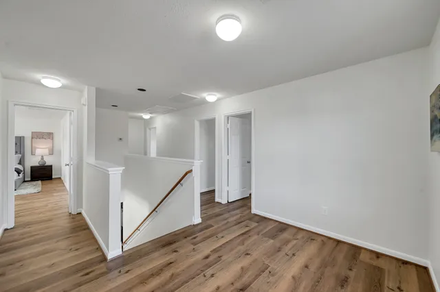 a view of a hallway with wooden floor and stairs