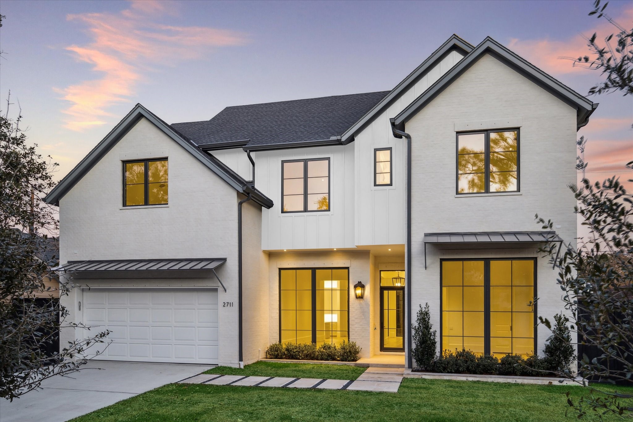 a view of a white house with large windows and a yard