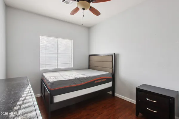 a bedroom with a bed dresser and wooden floor