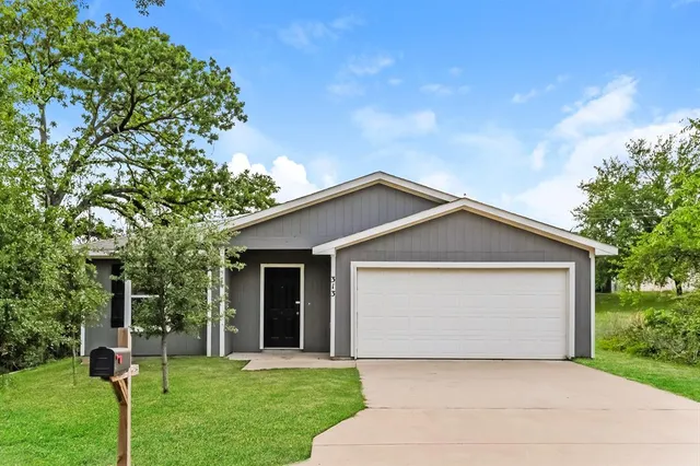 a front view of a house with a yard and trees