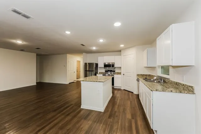 an empty room with wooden floor ceiling fan and windows