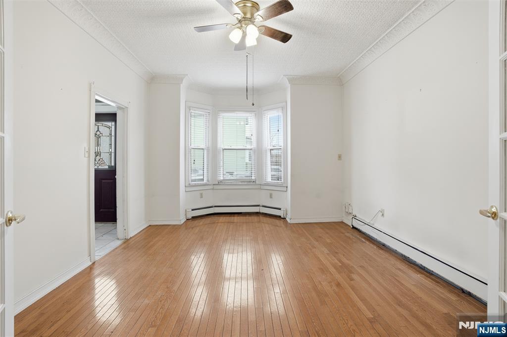 209 Hamilton Street Harrison, NJ 07029 - Photo 6 of 26 an empty room with wooden floor chandelier fan and windows