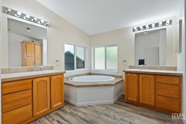 a bathroom with a granite countertop sink mirror and a bathtub